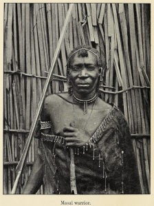 A Maasai warrior. Notice the man's body-wrap, armband, earrings, trinkets, necklace and general mode of dress, which, according to Oric Bates, is very similar to the traditional attire of the ancient Libyans. We now know that this is because the Maasai and other Great Lakes Nilotes borrowed much of their material culture from the Cushites of the Pastoral Neolithic. The ancient Cushites were closely related to the eastern Libyans, with whom they also shared many cultural aspects. This material culture eventually influenced neighboring Nilotic, Bantu and hunter-gatherer populations they came into contact with.